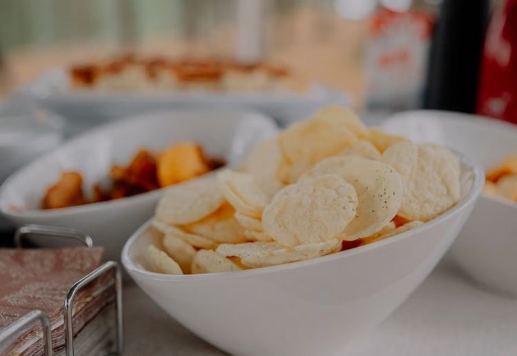 A variety of chips served in white bowls on a table, perfect for party snacks.