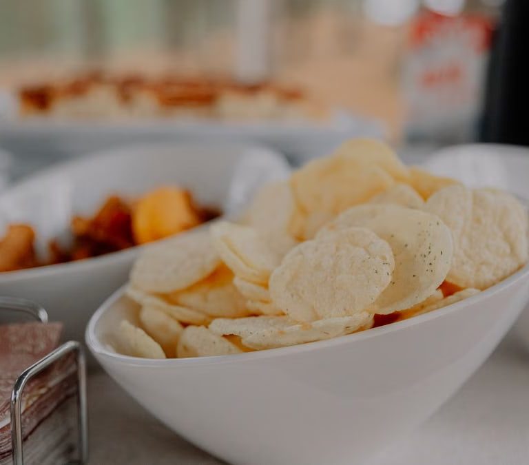 A variety of chips served in white bowls on a table, perfect for party snacks.